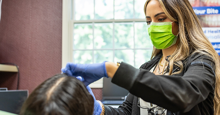 Woman smiling during a checkup with her dentist in New Baltimore