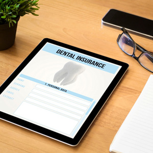 Dental insurance form on tablet on desk with notepad