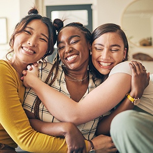 three friends smiling and hugging each other