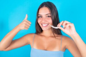 Woman giving thumbs up for Invisalign treatment