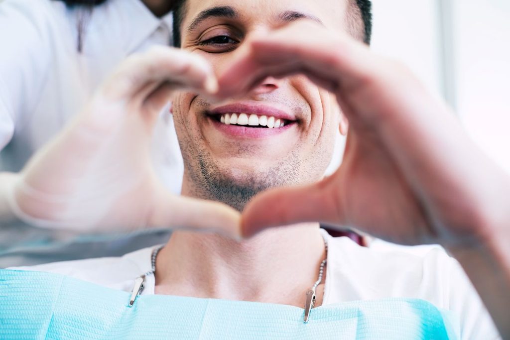A man making a heart with his hands at the dentist